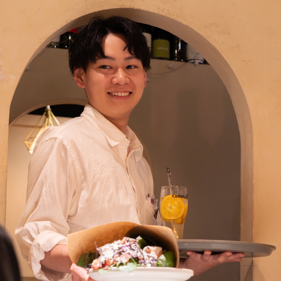 笑顔で料理提供をしている男性スタッフ