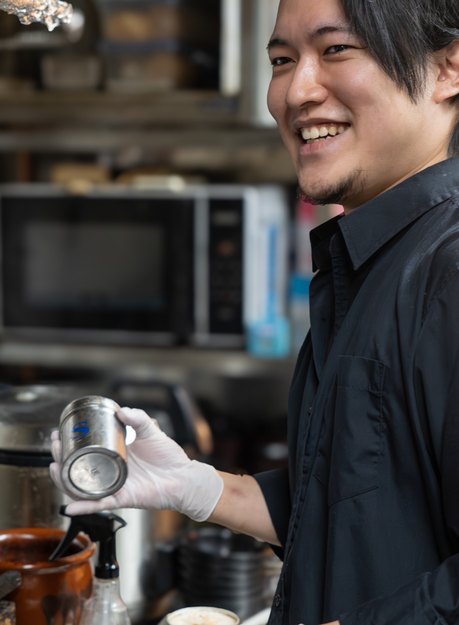 厨房で味付けをする男性スタッフ