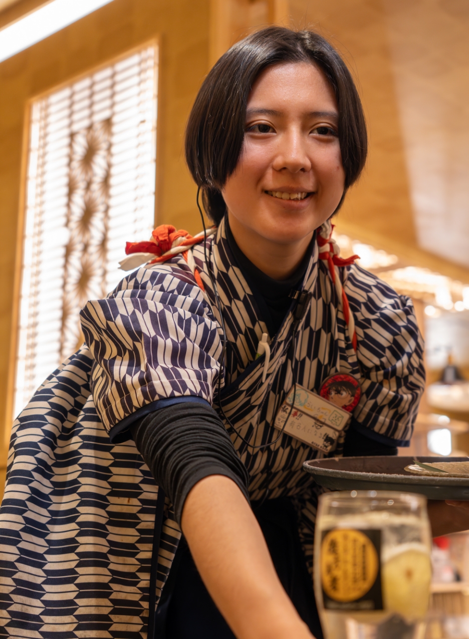和装でドリンクを提供する笑顔の女性スタッフ