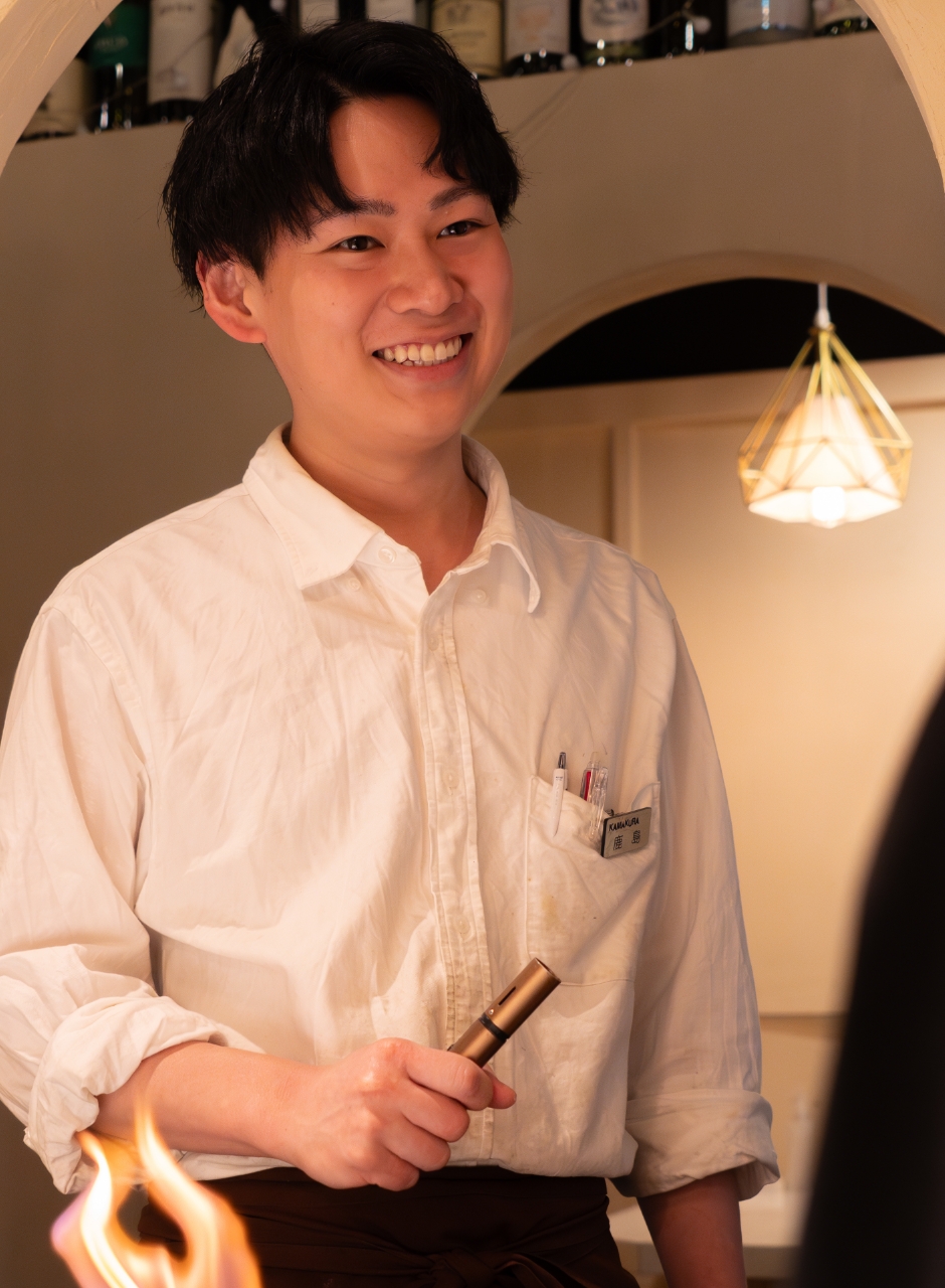 ギャルソンエプロンで提供する笑顔の男性スタッフ