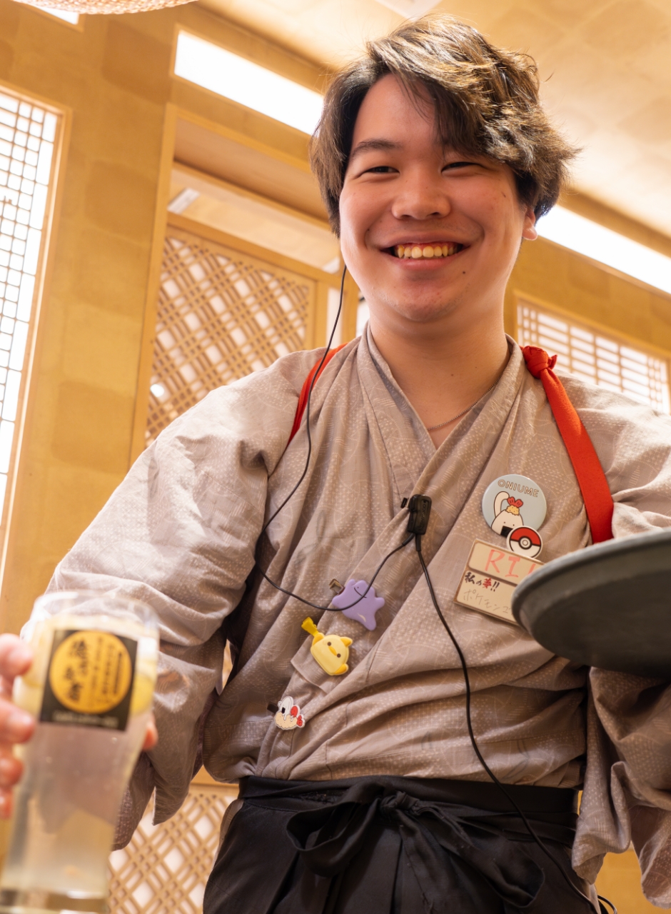 笑顔でドリンクを提供している和装男性スタッフ